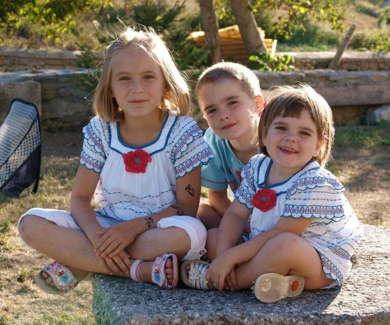 Photograph of three children sitting together outdoors