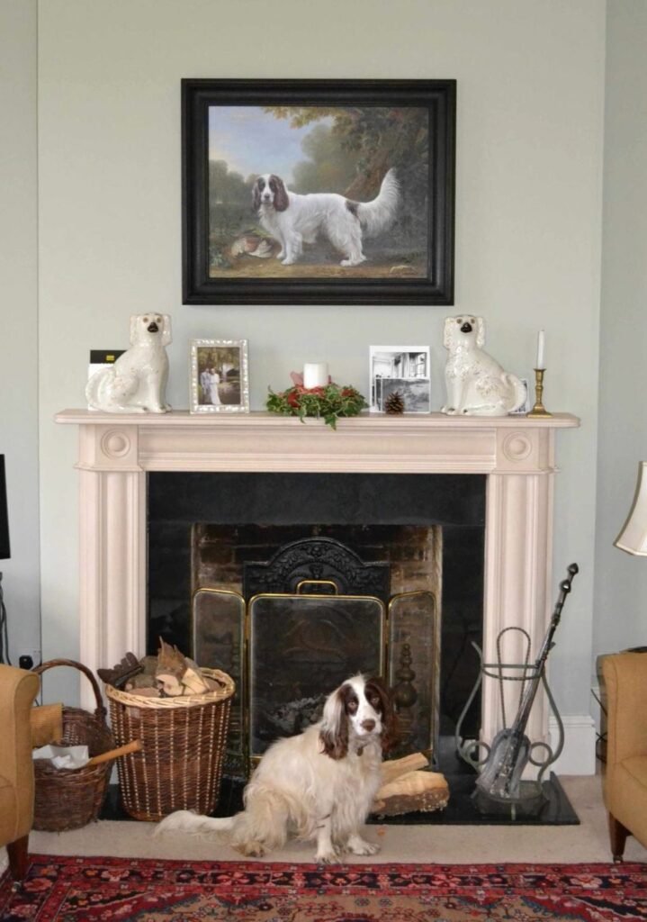 A commissioned dog portrait above a fireplace, with the dog lying on the hearth